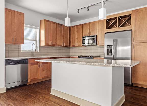 A kitchen with wooden cabinets and a white island.