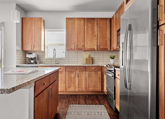 A kitchen with wooden cabinets and a stainless steel refrigerator.