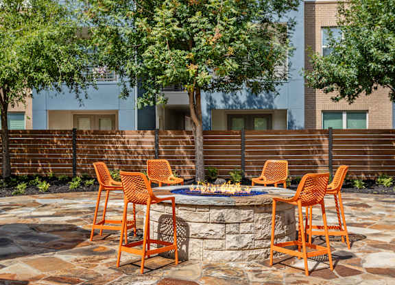 A patio with a fire pit and chairs.