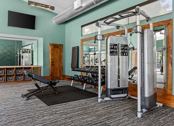 A gym with a variety of equipment including a weight machine and a bench.
