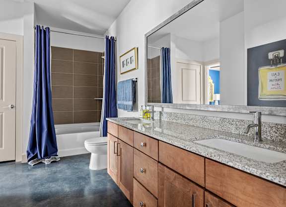 A bathroom with a toilet, sink, and blue curtains.