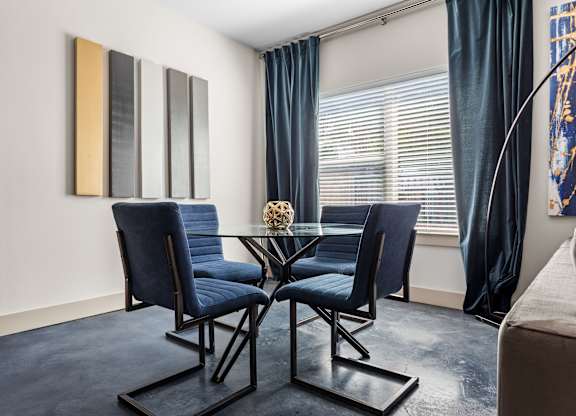 A dining room with a glass table and blue chairs.