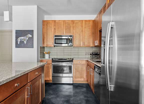 A kitchen with wooden cabinets and a stainless steel refrigerator.