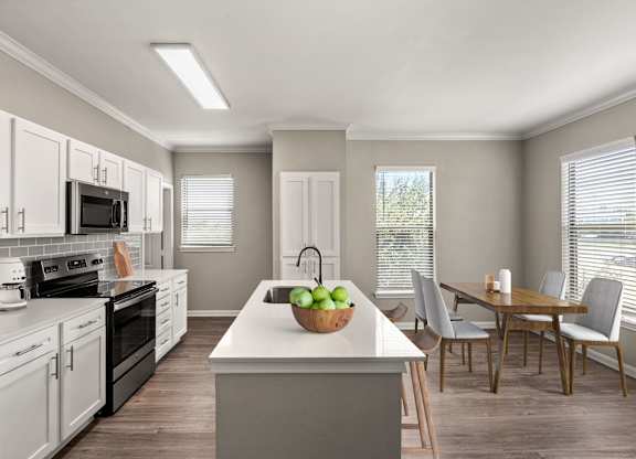 A kitchen with a white countertop and a bowl of green apples on it.