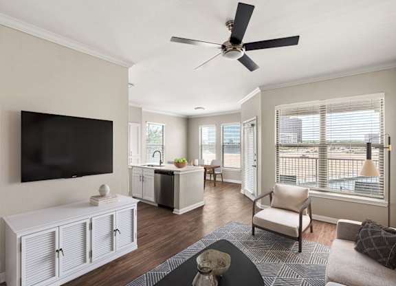 A living room with a television, a couch, and a ceiling fan.