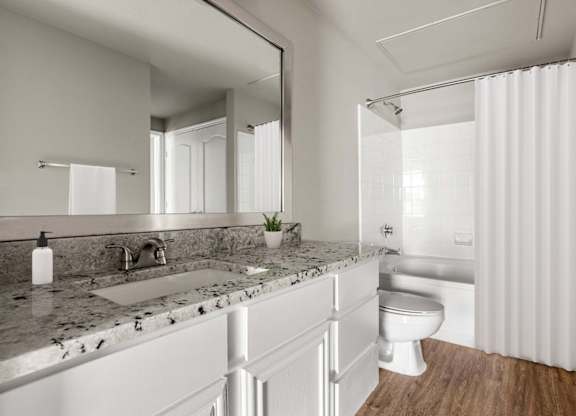 A modern bathroom with a marble countertop and white fixtures.