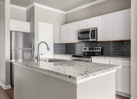 A kitchen with a marble countertop and stainless steel appliances.