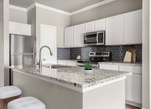A kitchen with a marble countertop and white cabinets.
