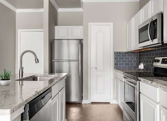 A kitchen with a refrigerator, sink, and oven.