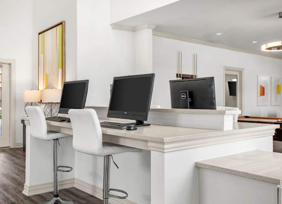 A white desk with two monitors and a laptop.