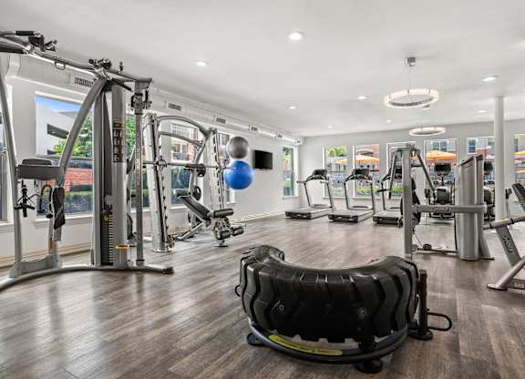 A gym with a variety of equipment including treadmills, weights, and exercise machines.