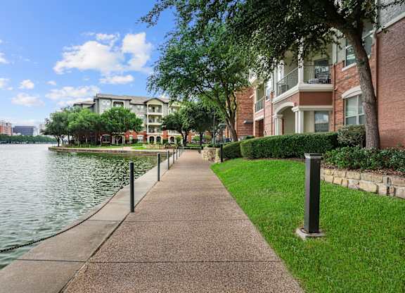 A walkway next to a body of water with a building in the background.