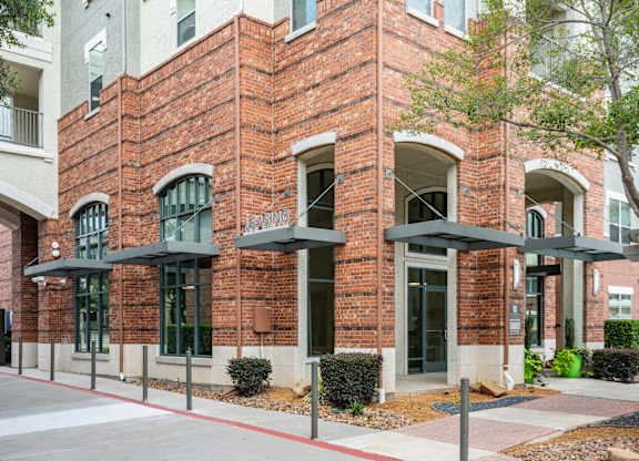 A red brick building with a black awning and a white sign that says