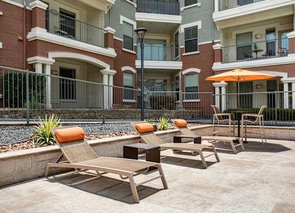 A patio with chairs and an umbrella in front of a building.