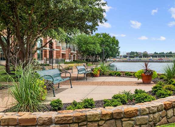 A park with benches and a pond in the background.