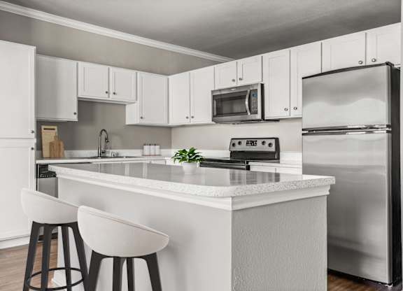 A modern kitchen with white cabinets and a white island.