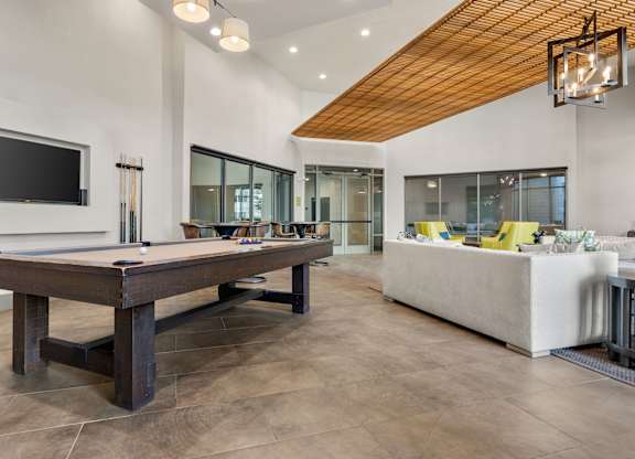 A billiard table is in the middle of a room with a television and a couch.