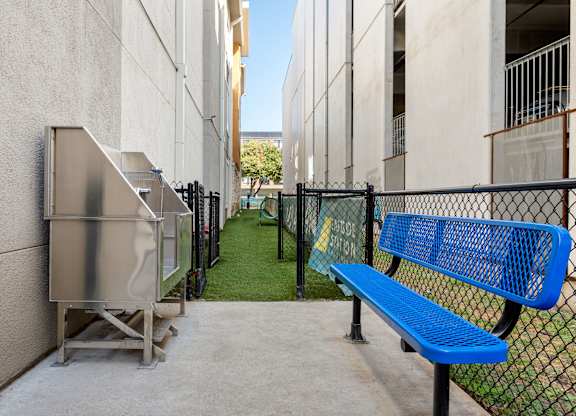 A blue bench sits in front of a metal fence.
