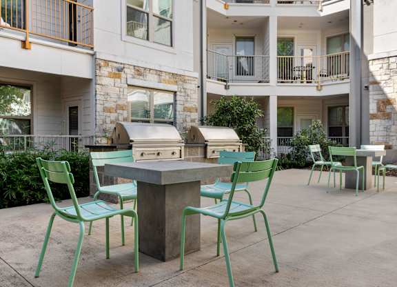 A patio with a table and chairs in front of a building.