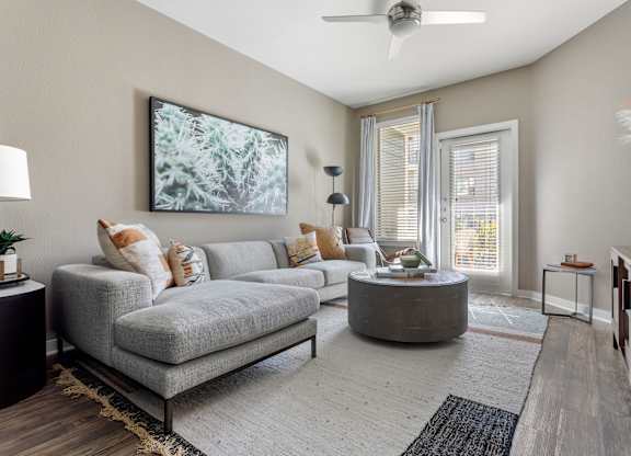 A living room with a grey sofa, a round coffee table, and a painting on the wall.