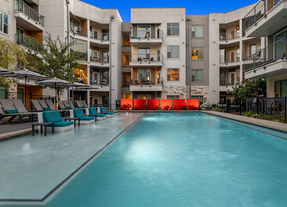 A long rectangular pool in front of apartment buildings.