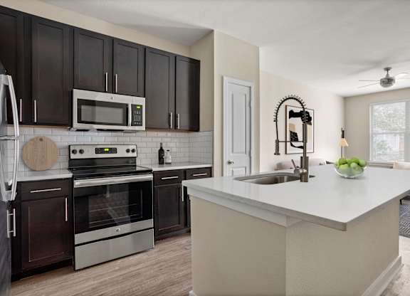 A modern kitchen with dark brown cabinets and stainless steel appliances.