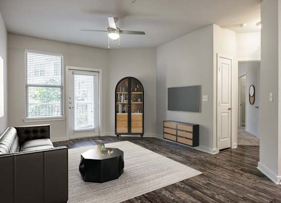A living room with a brown couch and a white ceiling fan.