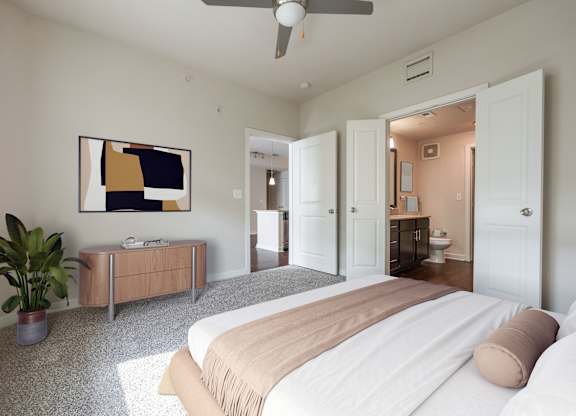 A bedroom with a bed, a plant, and a painting on the wall.