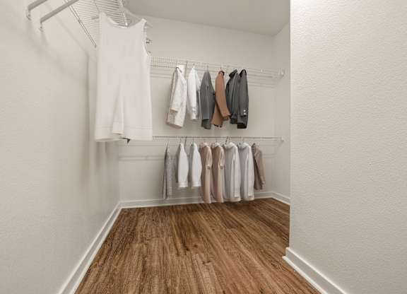 A white room with clothes hanging on a rack.