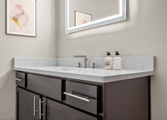 A bathroom with a sink, mirror, and cabinets.
