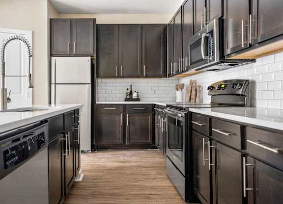 A kitchen with black appliances and wooden floors.