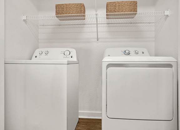 Two white front loading washing machines in a laundry room.