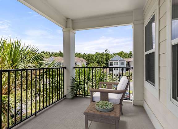 A balcony with a chair and a table with a plant on it.