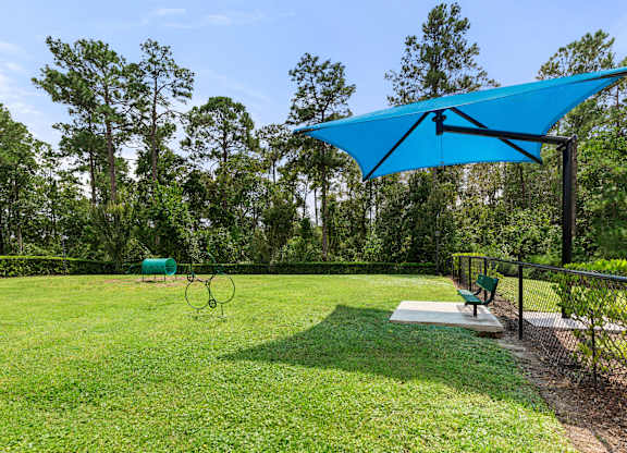 A blue umbrella is over a green lawn.