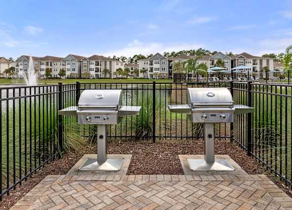 Two silver grills are in front of a black fence.