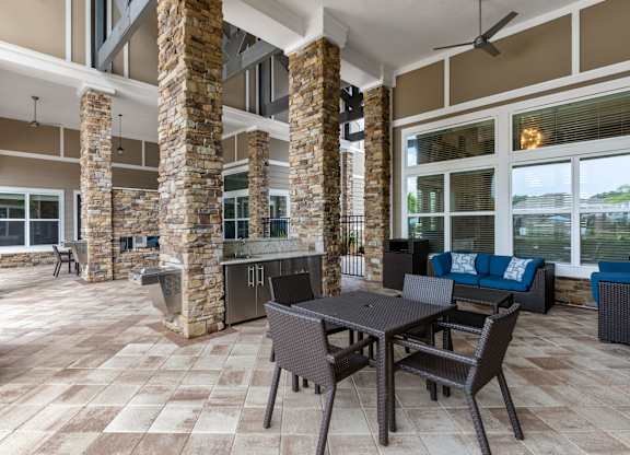 A patio with a table and chairs is surrounded by stone pillars.