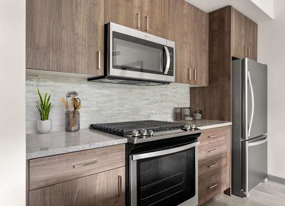 A modern kitchen with a stainless steel refrigerator, microwave, and oven.