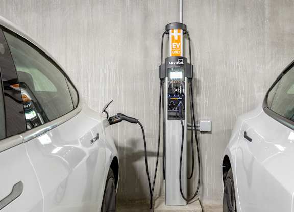 A white car is charging at a Leviton electric vehicle charging station.