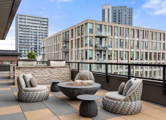 A patio with a fire pit and chairs.