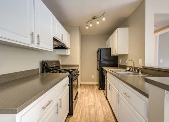A kitchen with black appliances and white cabinets.