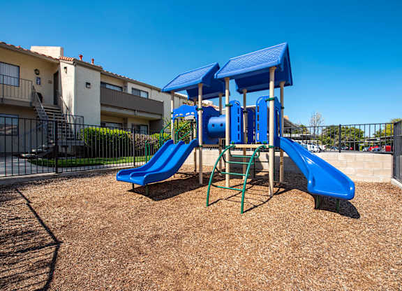A playground with a blue slide and a blue canopy.