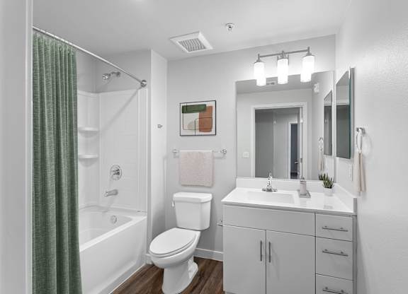 A white bathroom with a toilet, sink, and shower.