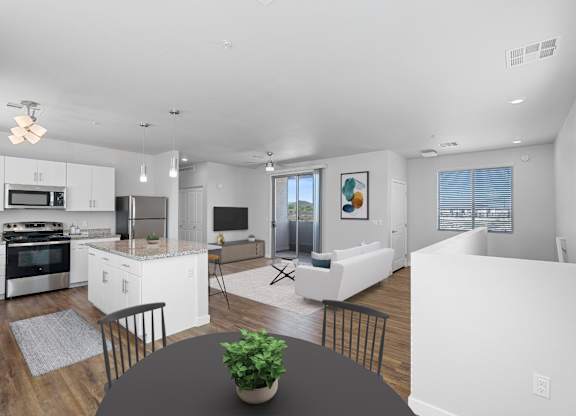 A modern kitchen with white cabinets and appliances, a dining table with a plant on it, and a living room with a couch and a painting on the wall.