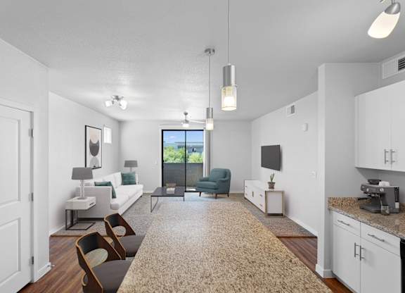 A well-lit, modern living room with a large window and a kitchen area.