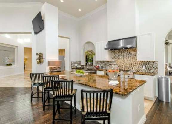 A kitchen with a granite countertop and black chairs.