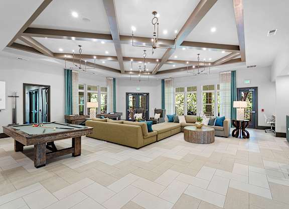 A large, well-lit room with a pool table and comfortable seating.
