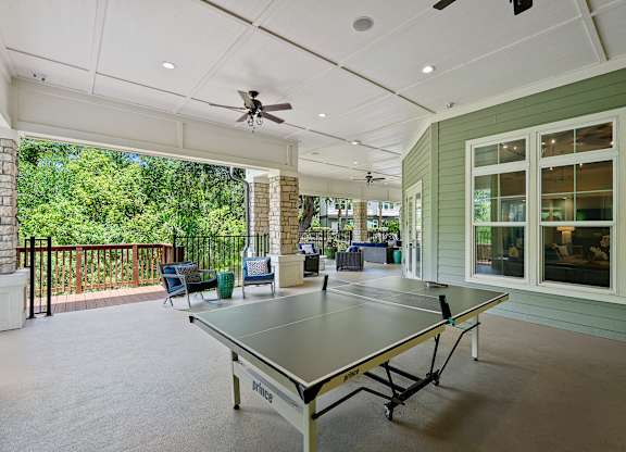 A ping pong table is in the middle of a room with a ceiling fan.
