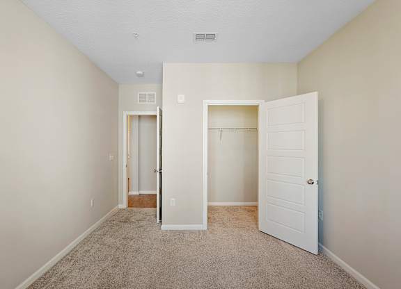 A room with a carpeted floor and two white doors.