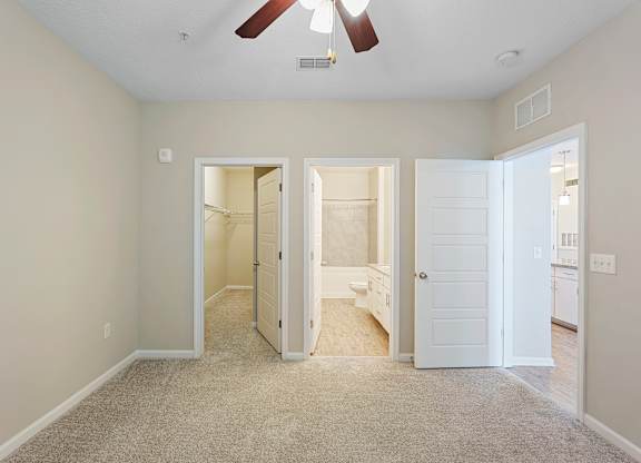A room with a ceiling fan and three open doors.