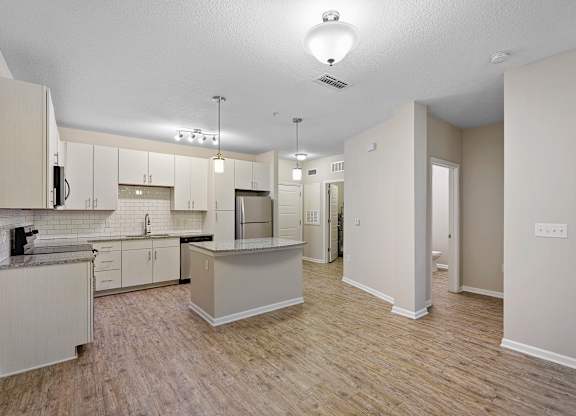 A kitchen with white cabinets and a wooden floor.